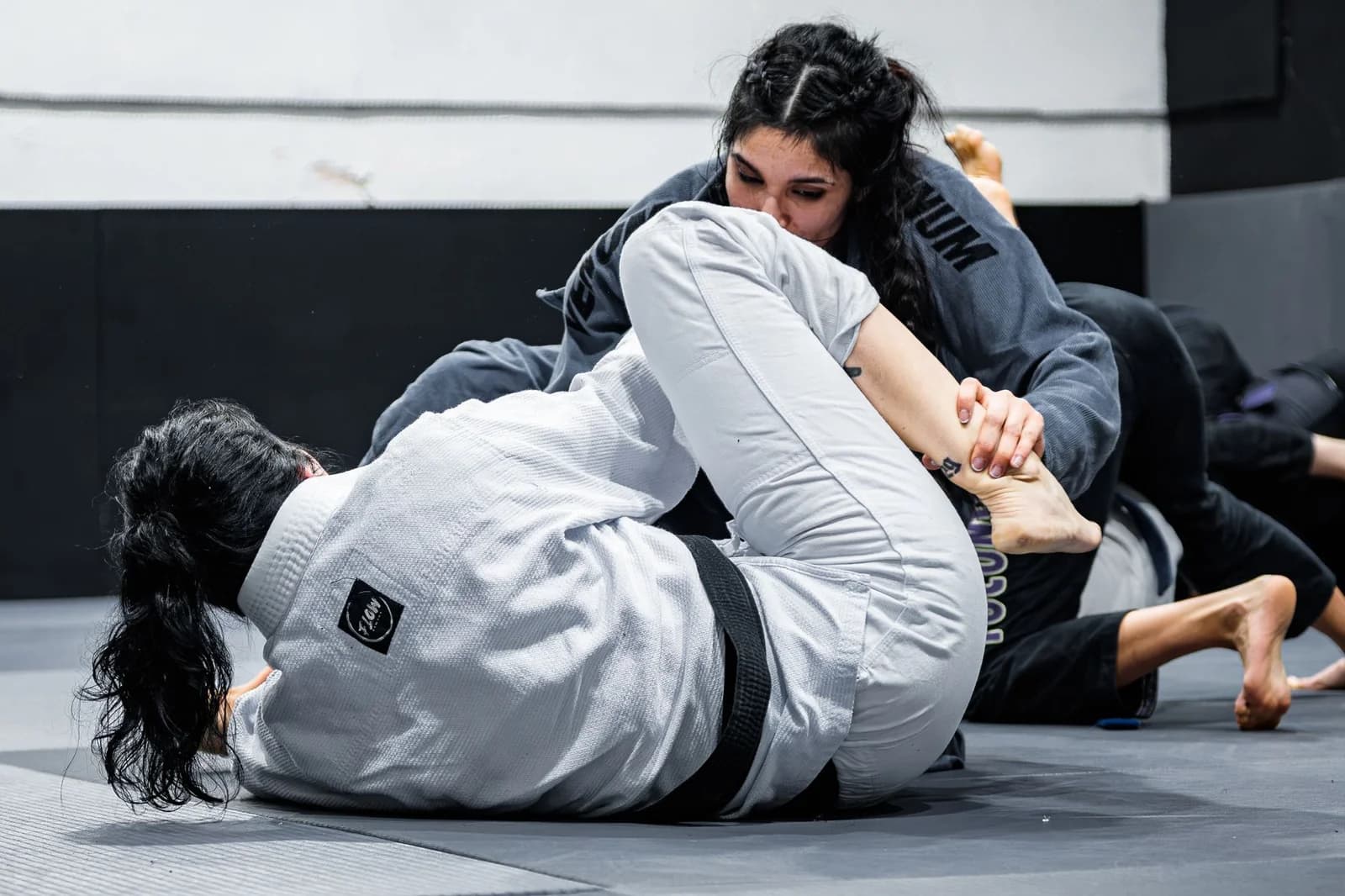 Atleta trabalhando a passagem de guarda sobre a guarda da adversária durante treino de Jiu-Jitsu com kimono. Foto de Eduard Perez via Pexels.